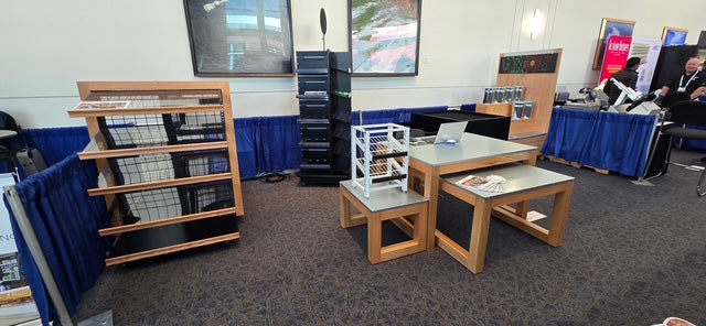 Display area with bookshelves, tables, and chairs in a room setting.