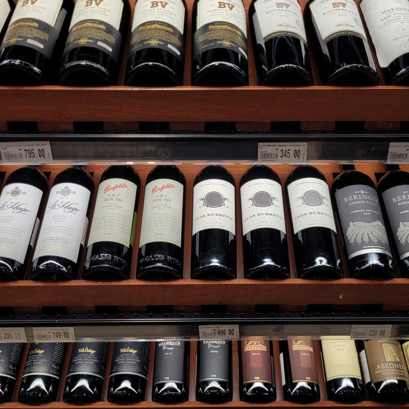 Wine rack showing various bottles of red wine on a grocery store display