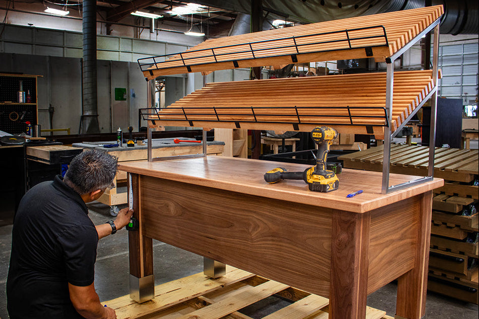 Woodworker man applies finishing touches to a custom-build wooden bakery display